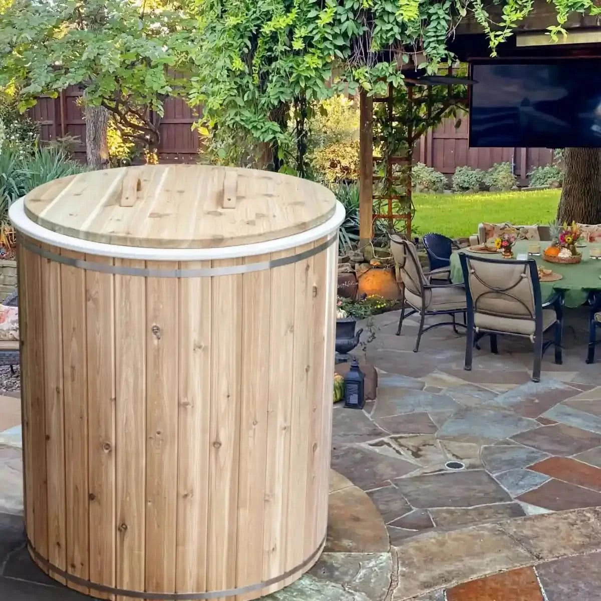 An exterior view of the Dundalk Leisure Craft Baltic Plunge Tub (CT33BP) with its wooden body and a matching wooden cover with handles, placed on a patio.