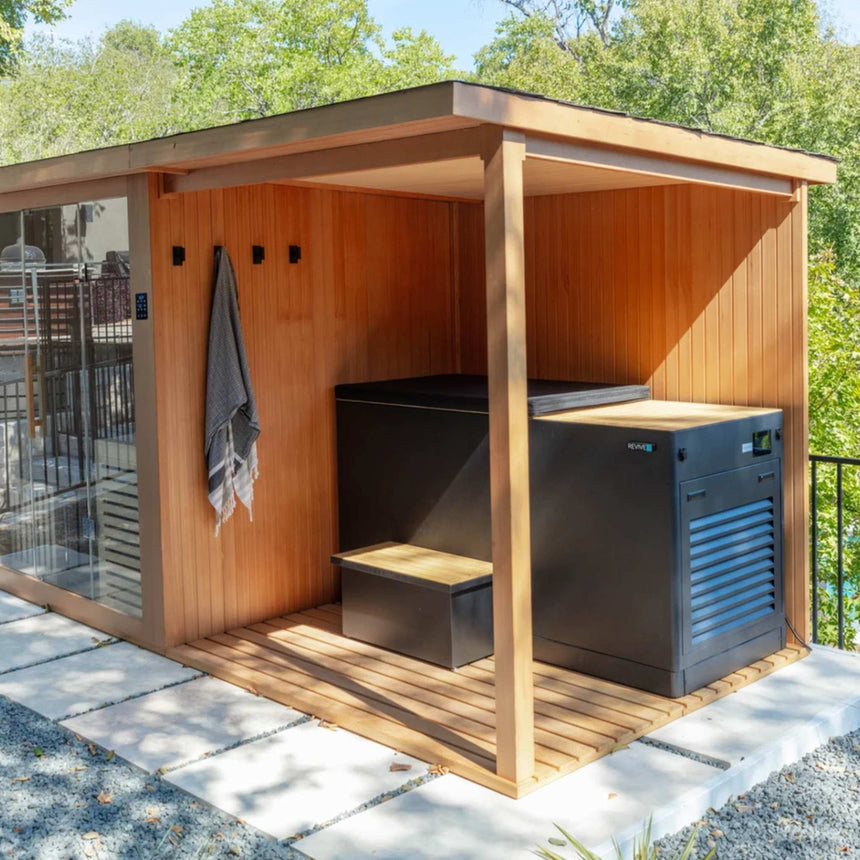 Covered deck of the Revive 4 Person Extended Sauna outdoors, holding the Revive Luxury Plunge with its cover and matching step, with a towel hanging on the deck wall