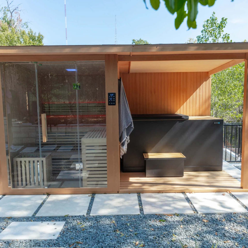 Revive 4 Person Extended Sauna outdoors on concrete pavers, with red LED lighting in the sauna and the Revive Luxury Plunge and its step under the covered deck