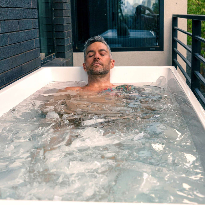 Man soaking in icy water in the Revive Acrylic Plunge outdoors