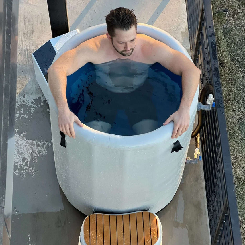Top view of a man soaking in the Revive Inflatable Barrel Plunge, with the inflatable step in front