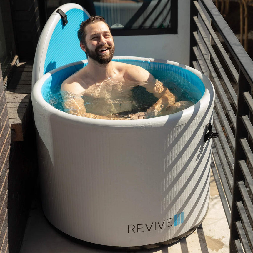 Man smiling in the Revive Inflatable Pod Plunge on a narrow balcony
