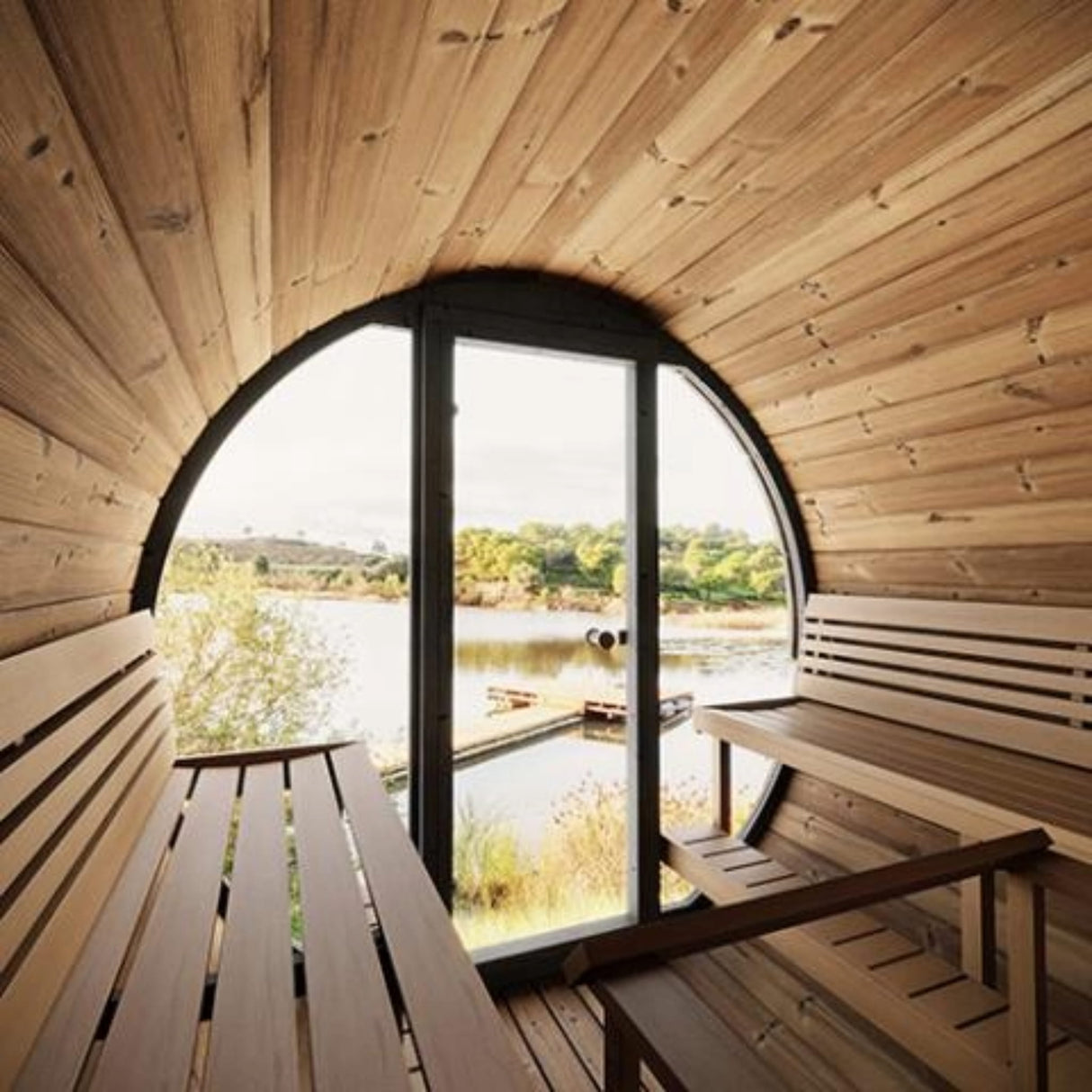 SaunaLife Model E8W premium outdoor sauna interior with panoramic glass front overlooking a lake and wood benches.