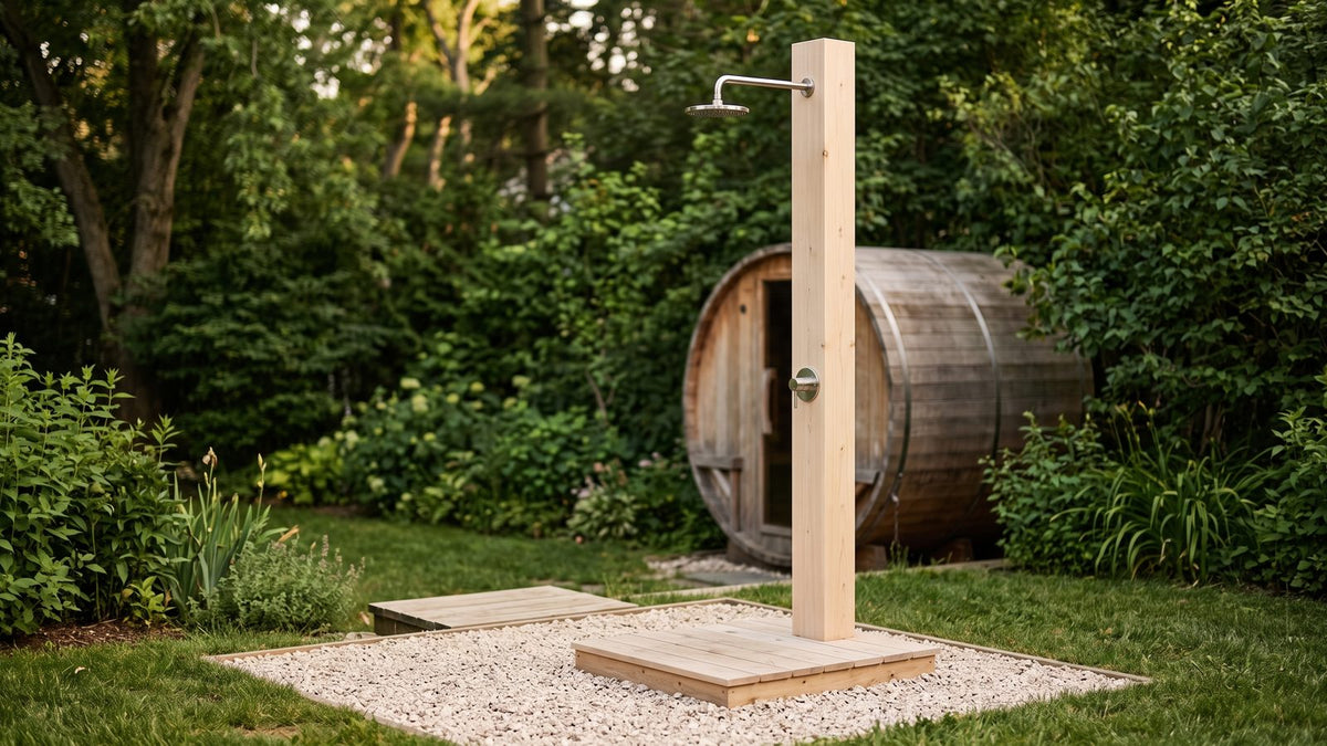 Outdoor shower for a sauna: a freestanding cedar pillar shower on a gravel pad beside a barrel sauna