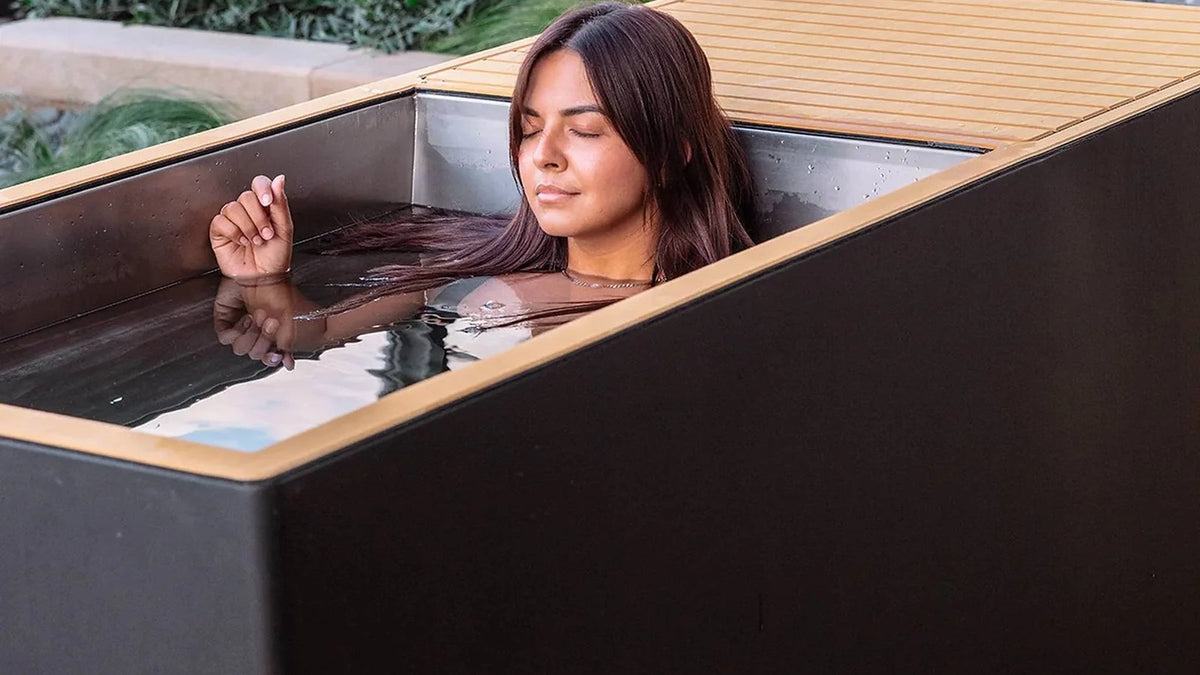 Revive cold plunges: a woman soaking in the stainless steel tub of the Revive Luxury Plunge outdoors