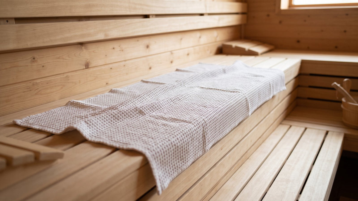 Sauna towel spread along the upper bench of a wooden sauna