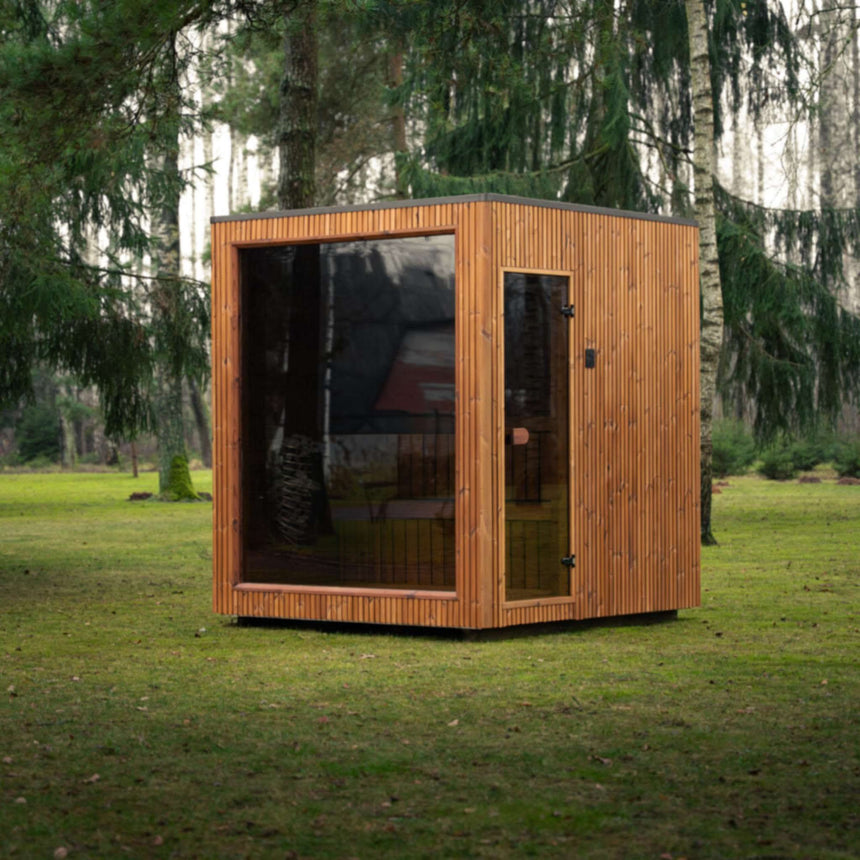 Celsium Jonas Classic outdoor sauna with a bronze-tinted glass front and full-height glass door on a forest lawn