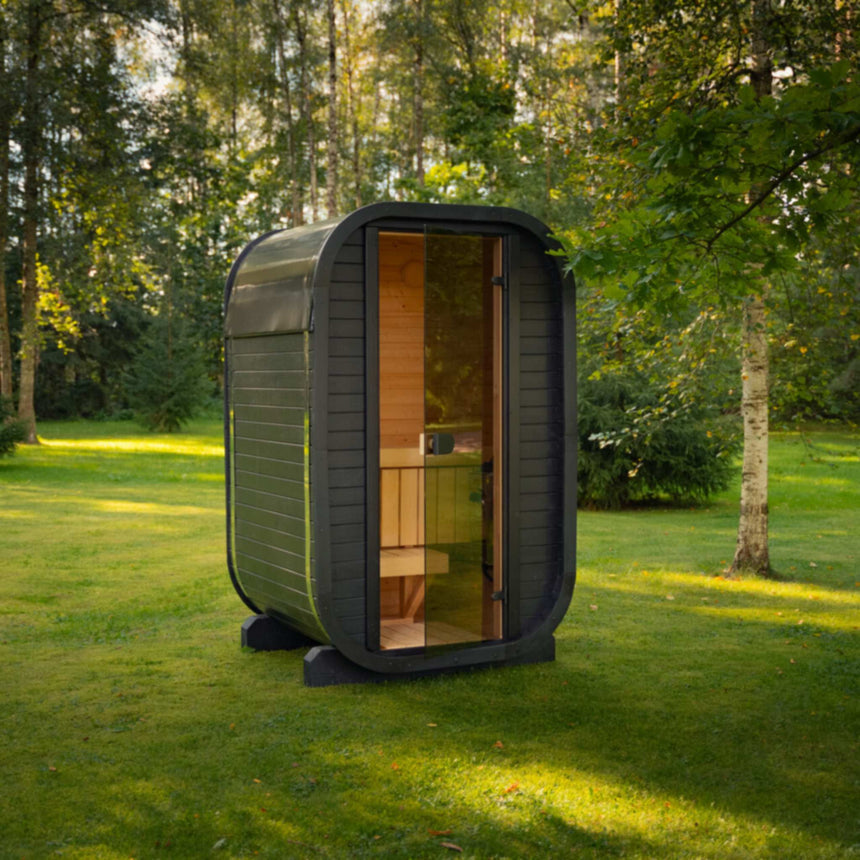 Dark Celsium Ula Micro Compact outdoor sauna on a lawn, shown with a timber front and a central glass door