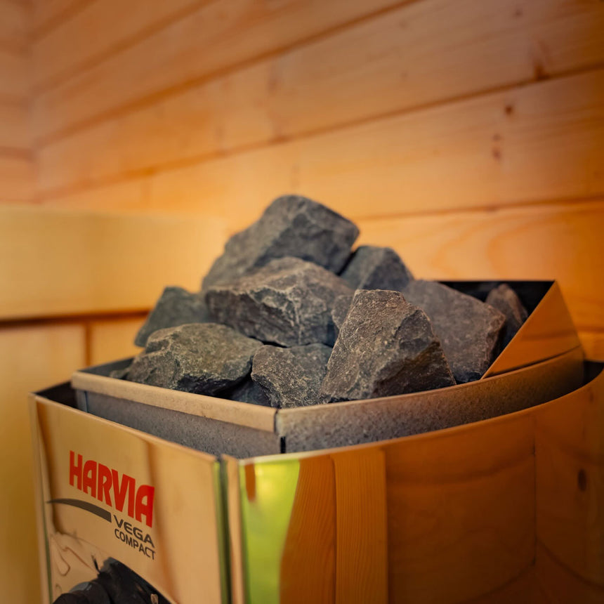 Harvia Vega Compact sauna heater filled with stones, shown inside the Celsium Ula Micro Compact