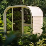Celsium Ula Mini outdoor sauna with a light finish and a full glass front in a garden