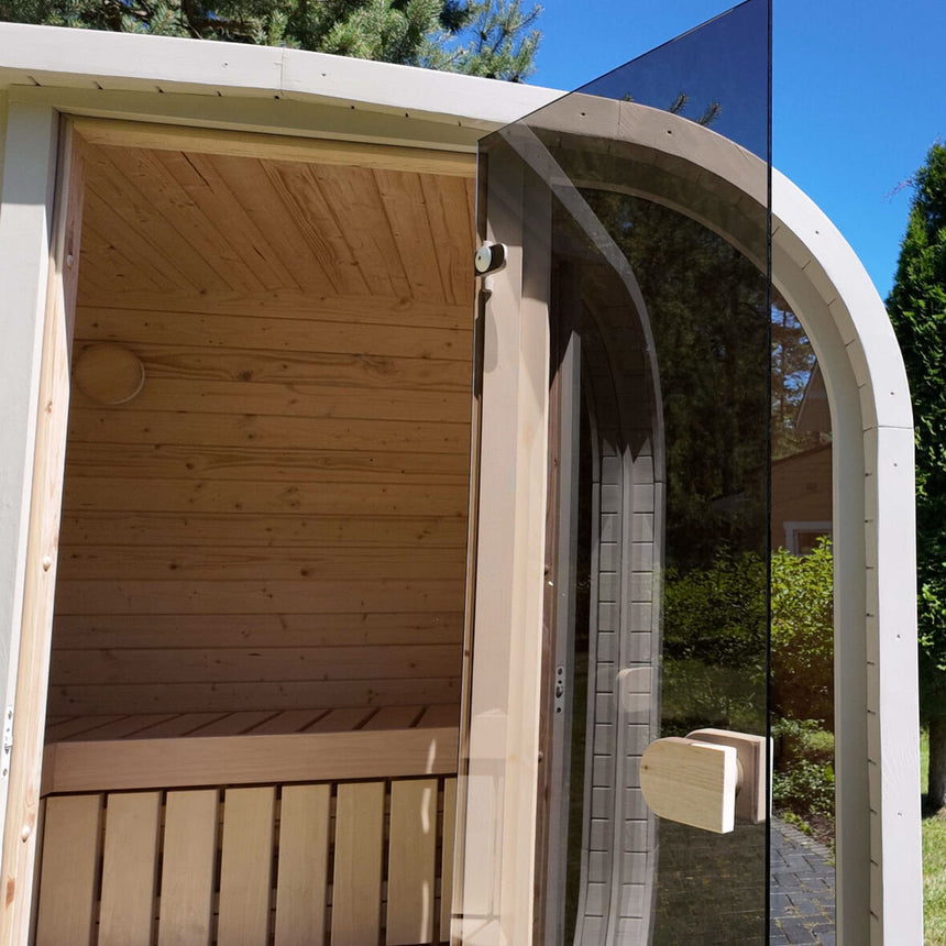 Light-colored Celsium Ula Mini outdoor sauna with its tinted glass door open to the benches inside