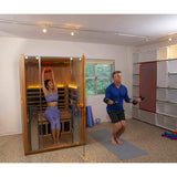 Couple using Clearlight Sanctuary 2 infrared sauna in home gym with fitness equipment
