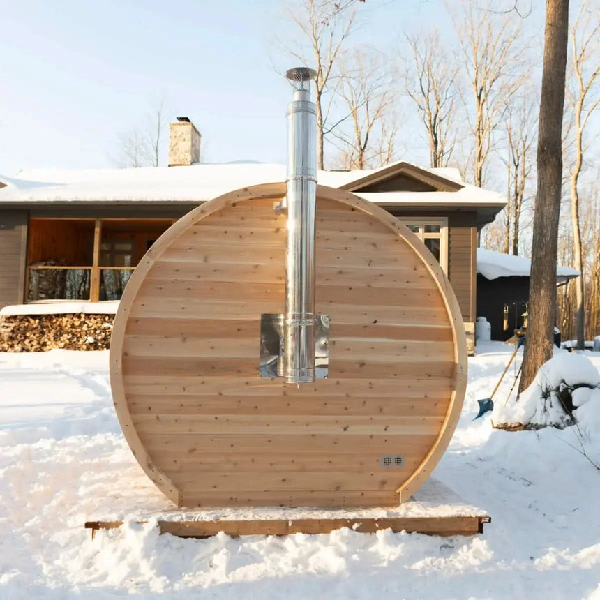 The back exterior of a Dundalk LeisureCraft CT Elation Sauna (CTC2424E) in a snowy winter setting, highlighting the chimney for the wood stove.