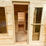 View from the outside of a Dundalk LeisureCraft Canadian Timber Georgian Cabin Sauna with Changeroom (CTC88CE) looking through the doorway and into the sauna.