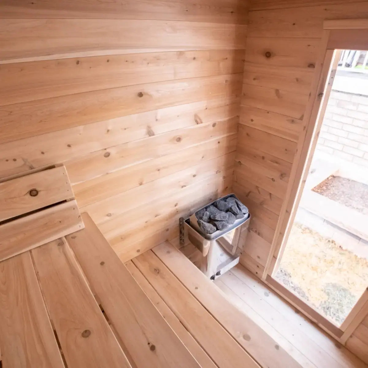 A close-up view of the interior of a Dundalk LeisureCraft CT Granby Cabin Sauna (CTC66E), highlighting the electric sauna heater and wooden benches.