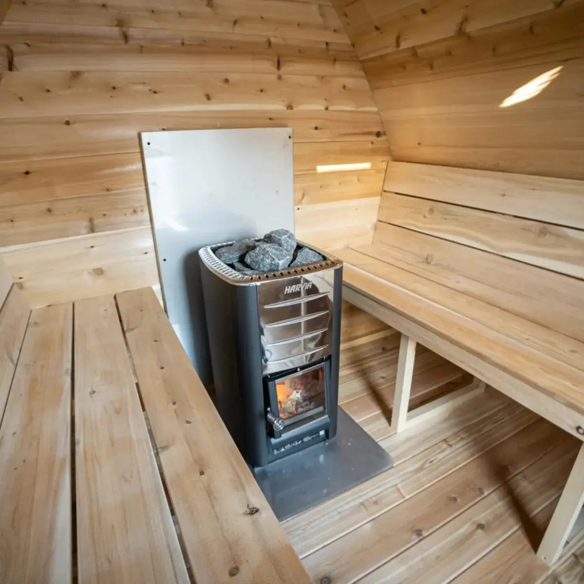 The interior of a Dundalk LeisureCraft Canadian Timber MiniPOD Sauna (CTC77ME), showing the wood-burning heater and interior benches.
