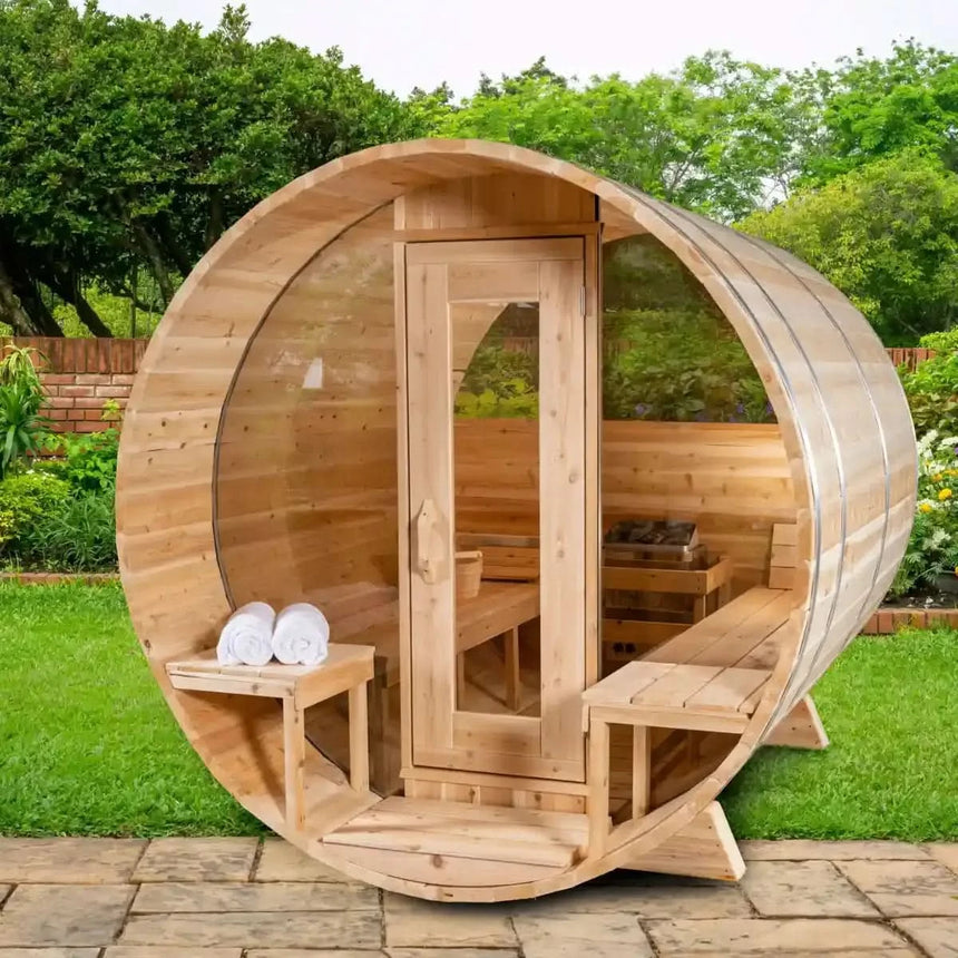 A wide-angle exterior view of the Dundalk Leisure Craft CT Serenity MP Barrel Sauna (CTC2245MPE), showing the front with a full glass door, benches, and an optional heater visible inside.
