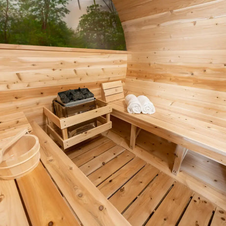 An interior shot of the Dundalk Leisure Craft CT Serenity MP Barrel Sauna (CTC2245MPE), showcasing the electric sauna heater, hot stones, and the interior benches.