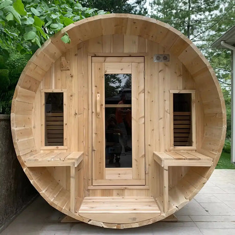 A front exterior view of the Dundalk Leisure Craft CT Tranquility MP Barrel Sauna (CTC2345MPE), featuring two small benches and windows flanking the main entry door.
