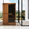 Finnmark FD-4 Trinity 2-person infrared steam sauna exterior with Thermo-Aspen wood finish and tempered glass door on outdoor patio.