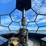 Harvia Legend 240 Green Flame stove installed in a geodesic glass sauna dome with visible WL300 smoke pipe cover and chimney.