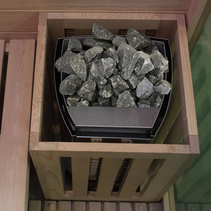 Harvia heater filled with sauna stones inside the wooden heater guard of the Revive 2 Person Traditional Sauna