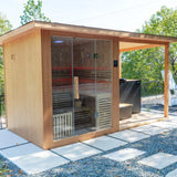 Three-quarter view of the Revive 4 Person Extended Sauna outdoors, showing the sauna's side wall with a vent, its glass front and the covered deck beside it with the Revive Luxury Plunge