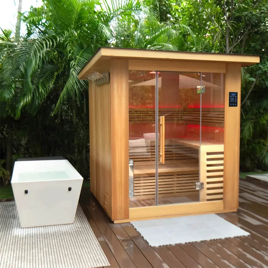 Revive 4 Person Traditional Sauna on an outdoor deck among palms, with red LED lighting inside and the Revive Acrylic Plunge, sold separately, beside it