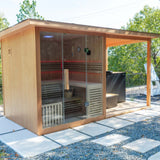 Revive 4 Person Traditional Sauna, sold separately, with red LED lighting inside and the deck extension on its right, outdoors on concrete pavers, with the Revive Luxury Plunge and its step, also sold separately, under the covered deck