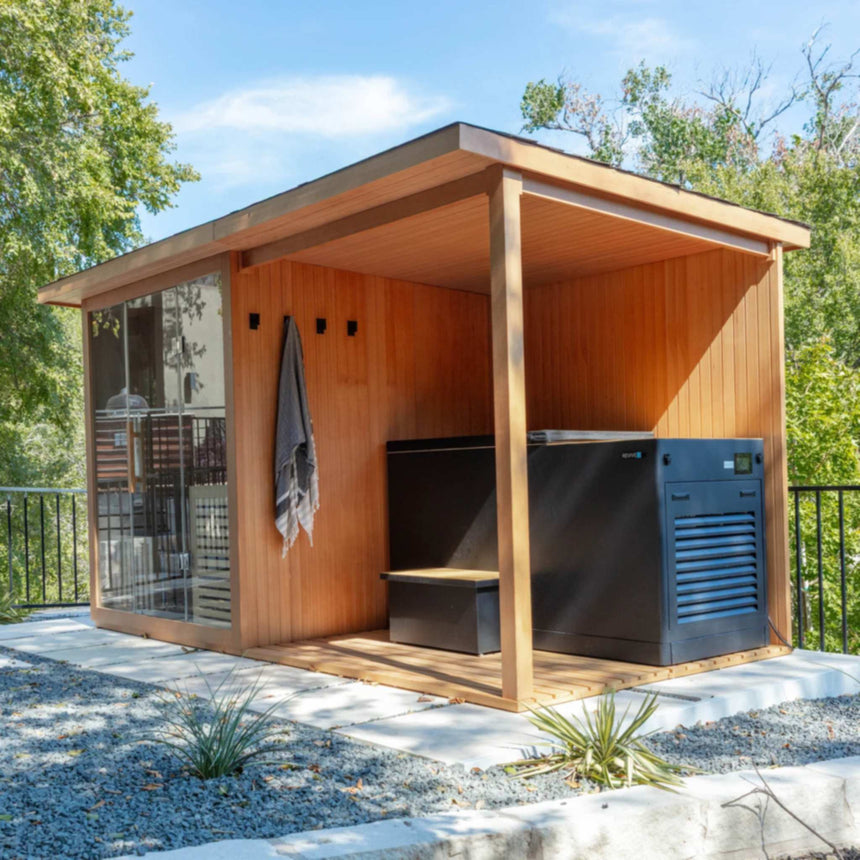 Three-quarter view of the Revive 4 Person Traditional Sauna Deck Extension outdoors, holding the Revive Luxury Plunge and its step, with a towel hanging on the wall beside the sauna's glass front; the sauna and plunge are sold separately