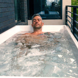 Man soaking in icy water in the Revive Acrylic Plunge outdoors