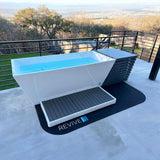 Revive Chiller Cover at the end of a water-filled Revive Acrylic Plunge on a terrace, with the Revive Acrylic Basin on a protective mat in front; the plunge, basin and mat are sold separately