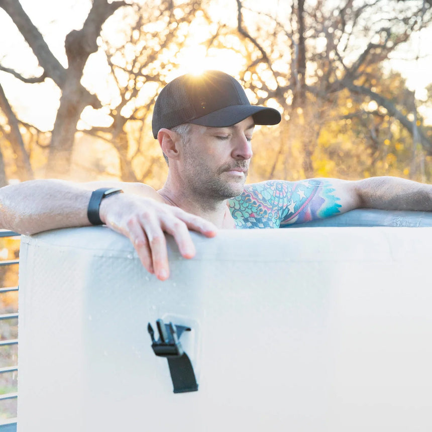 Man resting his arms on the rim of the Revive Inflatable Barrel Plunge outdoors
