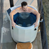 Top view of a man soaking in the Revive Inflatable Barrel Plunge, with the inflatable step in front