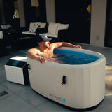 Man soaking in the Revive Inflatable Tub on an outdoor patio, shown with an optional Revive chiller, sold separately