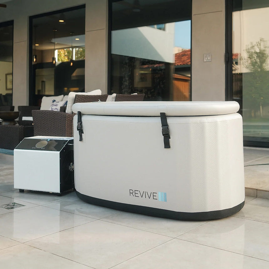 Revive Inflatable Tub with its strapped cover on an outdoor patio, shown with an optional Revive chiller, sold separately
