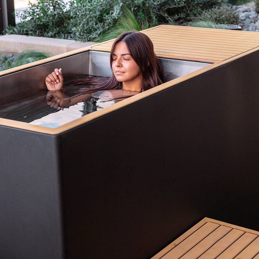 Woman soaking in the stainless steel tub of the Revive Luxury Plunge outdoors