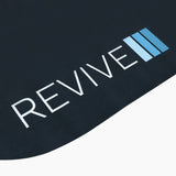 Close-up of the white and blue Revive logo near a corner of the Revive Padded Protective Mat