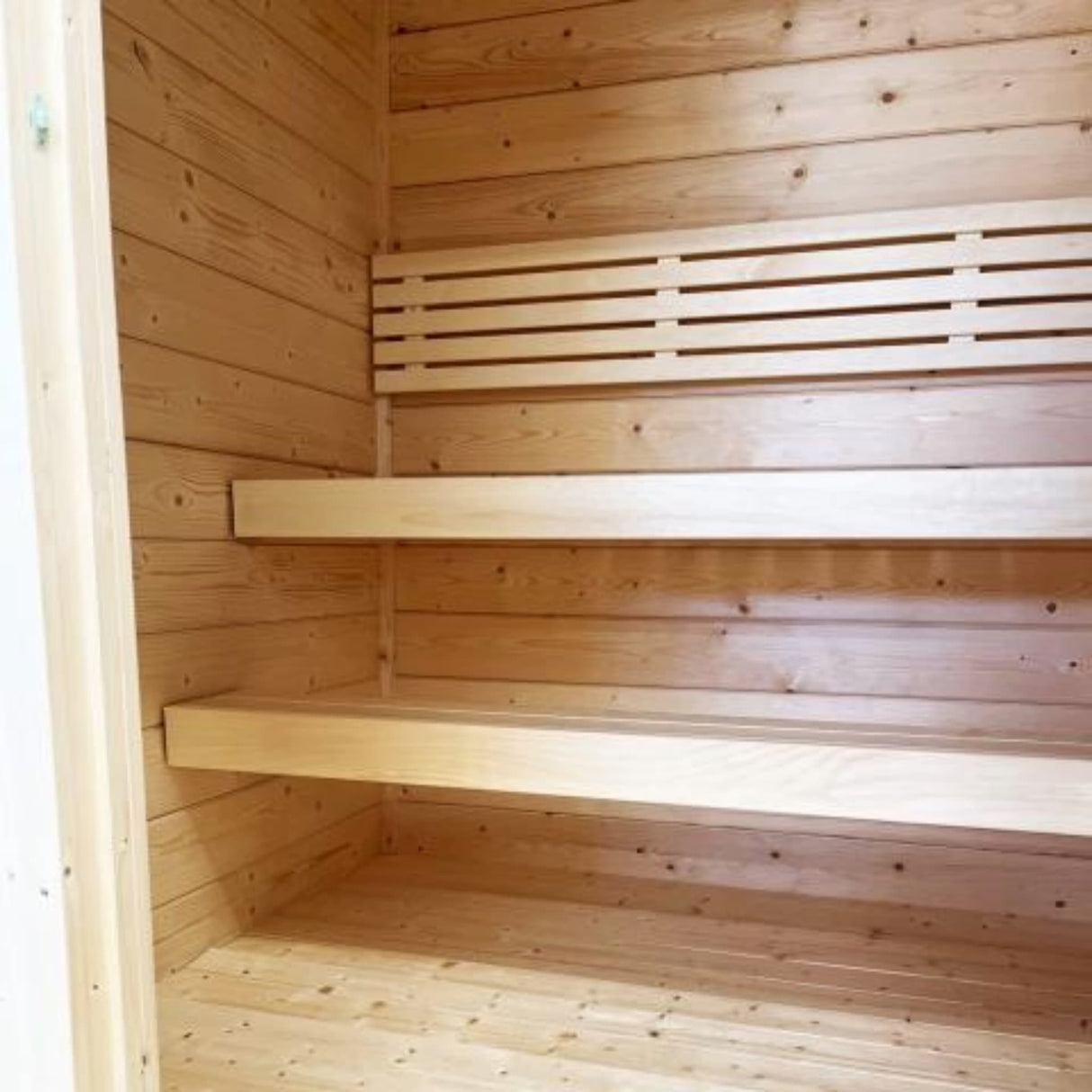 SaunaLife G2 outdoor sauna interior showing two-tier knotless aspen benches and backrest with Nordic spruce walls.