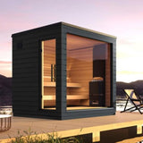 SaunaLife Model G6 5-person pre-assembled outdoor sauna with black painted spruce exterior and full glass front wall at sunset.