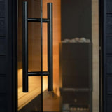 SaunaLife G6 Garden Series outdoor sauna entrance with double-glazed clear glass door and black aluminum handle at dusk.
