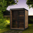SaunaLife Model GL4 4-person Garden Luxury outdoor sauna at night with LED eaves lighting, bronze glass front and black trim.