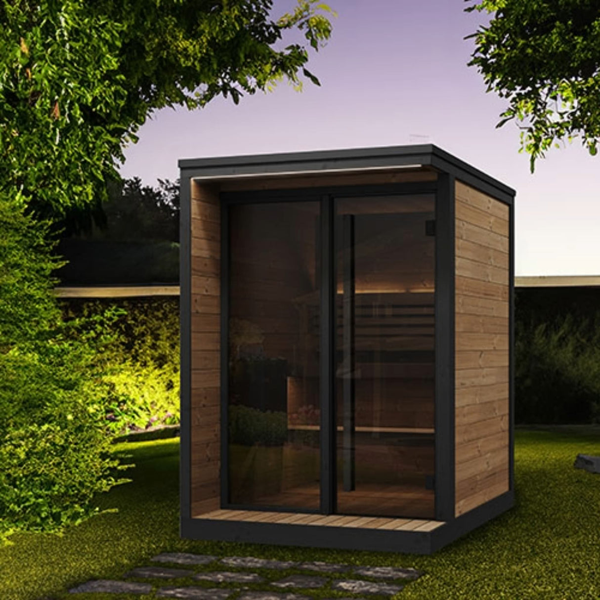 SaunaLife Model GL4 4-person Garden Luxury outdoor sauna at night with LED eaves lighting, bronze glass front and black trim.